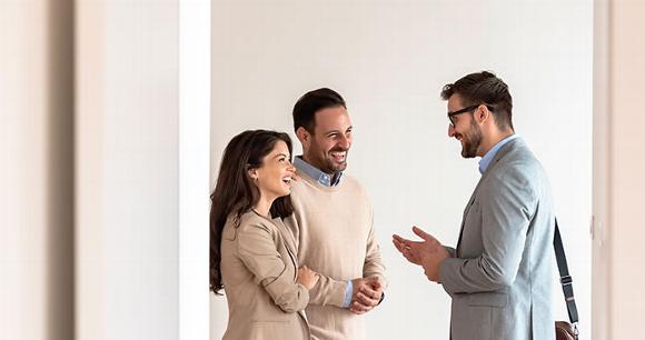 Couple talking with professional surveyor in empty home